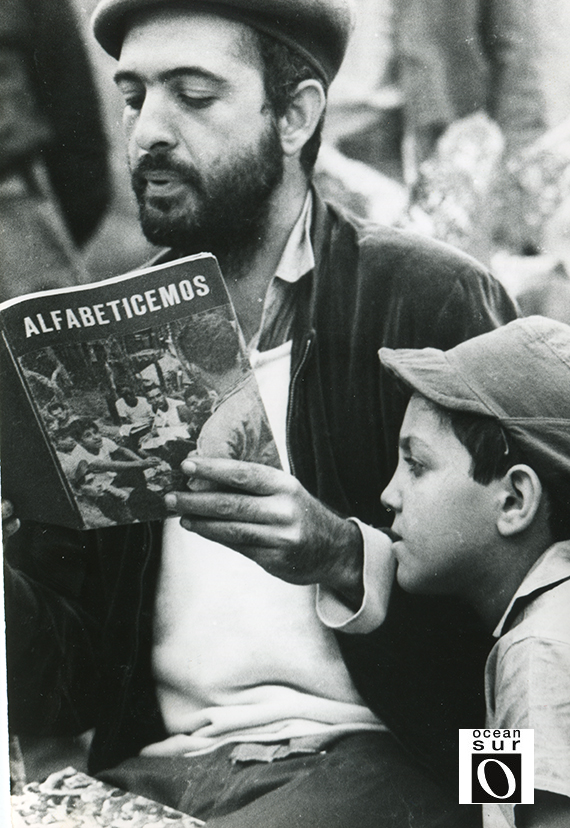 Campaña de Alfabetización: hombre y niño leyendo un cuaderno
